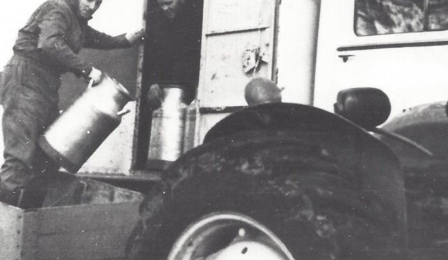 Jón A. Jónsson bílstjóri tekur við mjólkurdunkum Alexanders bónda í Hlíð.